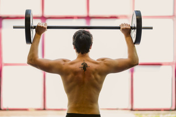 Man  is doing exercise with weight bar.