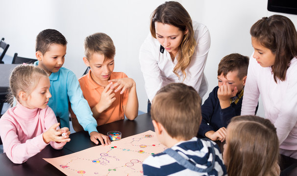 Children sitting at table with board game in classroom