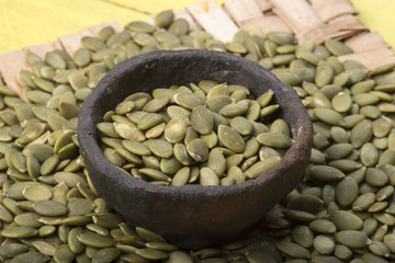 Raw hulled pumpkin seeds in primtive bowl
