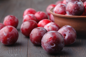 Plums in dish on dark wooden table