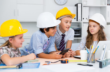 Teens engineers discussing draft at the table