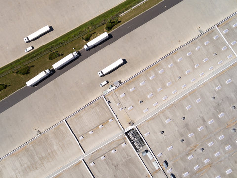 Aerial view of warehouse with trucks. Industrial background. Logistics from above. 