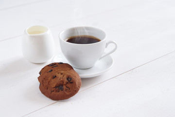 A cup of fragrant coffee with milk and cookies on the white background. Shortbread cookies with slices of chocolate and white cup of coffee.