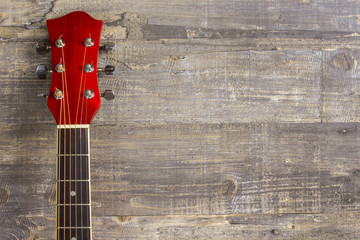 Guitar acoustic red, neck lying on a vintage background of wood on the background of old grunge boards. Place for text. View sverkhplastichnost Spanish, rectangular format music school game for