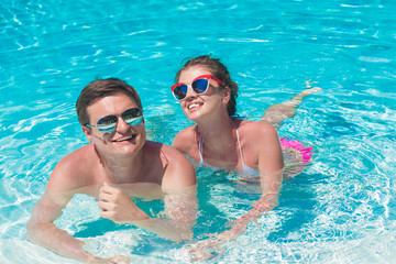 young couple relaxing and having fun by the luxury pool