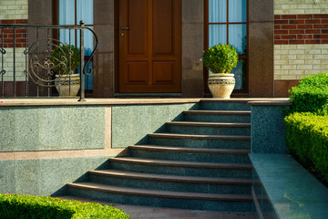 Entrance group in a modern stone house with marble steps into the house surrounded by landscape...