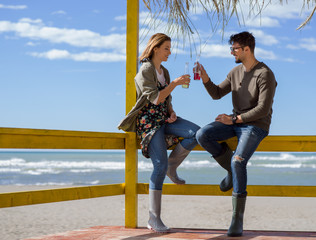 young couple drinking beer together at the beach