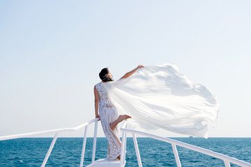Honeymoon sea cruise. Things consider for wedding abroad. Wedding ceremony sea cruise. Bride adorable white wedding dress sunny day posing on boat or ship. Advice and tips from wedding abroad experts
