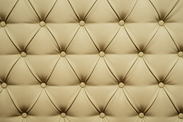 Fototapeta na wymiar Coach-type leatherette screed tightened with buttons. Natural chesterfield style quilted upholstery backdrop close up. background texture