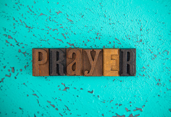Prayer Spelled in Wooden Type Set Block Letters on a Turquoise Background