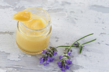 organic royal jelly in a glass bottle and full spoon on jar,with lavender decoration