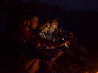 Obraz premium Couple enjoying with friends at night on the beach