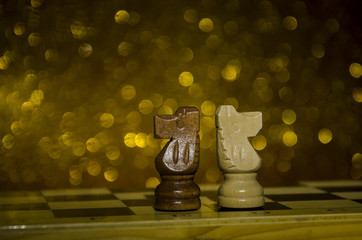 Piezas de ajedrez en fondo dorado brillante. Caballos de madera. © yaninaamira