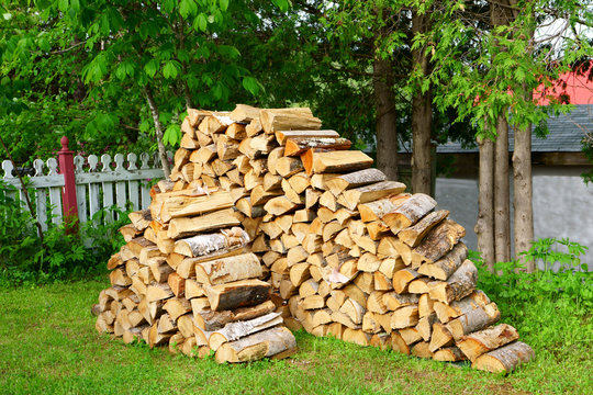 A pile of split logs in the backyard ready for a cold winter in order to heat the house.