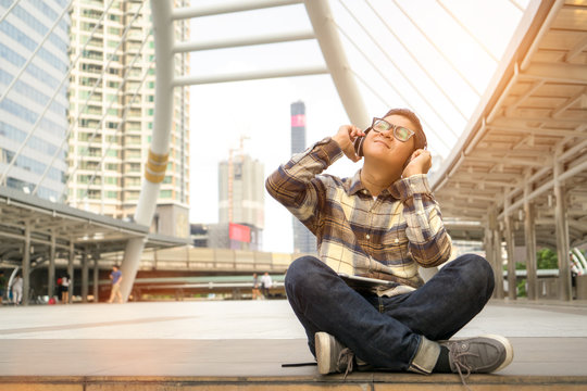 Asian man  listen to music in smartphone and happy on holiday with easy life. time to relax on city.