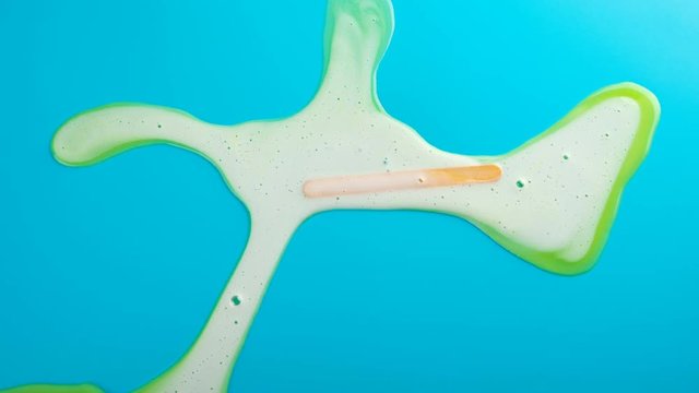 reverse studio shoot of yellow popsicle melting on blue time lapse