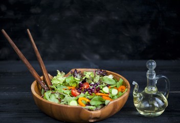Fresh mixed pomegranate salad and cherry tomatoes on a wooden plate, pouring olive oil