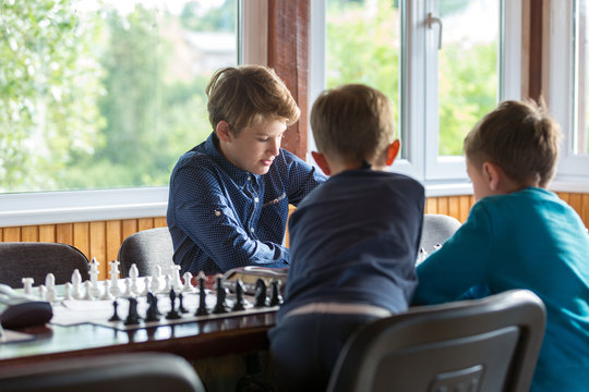 cute handsome boy in white tshirt plays chess with his rival in chess class. Education concept, intellectual game. Chess tournament, lesson, camp, training concept