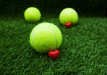 To tennis player with love shape and tennis ball on green grass