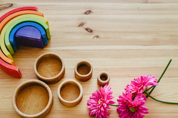 Group of round and empty wooden bowls and purple flowers with free space for text with montessori wood rainbows.