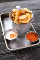 deep fried pickles in an old metal container with dipping sauces