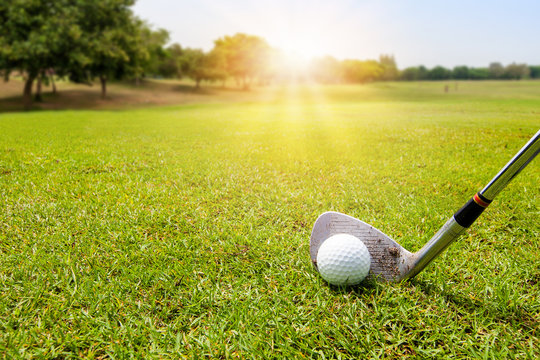 Golf ball on beautiful green grass with sunlight in morning time. Sport and recreation playground for golf club concept.	