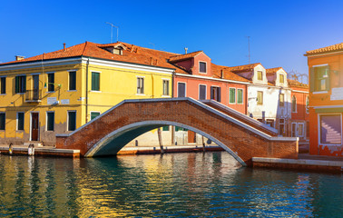 Fototapeta na wymiar Street canal in Murano island, Venice. Narrow canal among old colorful brick houses in Murano, Venice. Murano postcard, Venice, Italy.