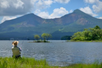 Fototapeta na wymiar 夏の湖畔・のんびりと釣りをする男性 
