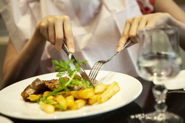 ステーキを切っている女性。クローズアップ。