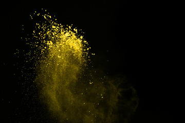 Abstract yellow dust explosion on black background. abstract yellow powder splatted on black...