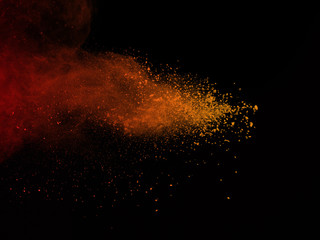 Abstract orange dust explosion on black background. abstract colored powder splatted on black...
