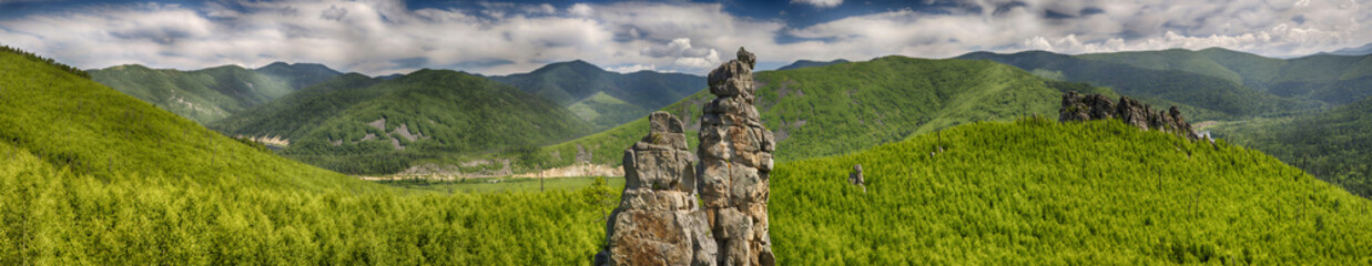 Panoramic landscape: a large rocky peak against the background of green mountains, hills and...