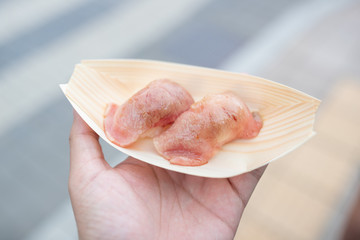 hand holding burned meat shushi.