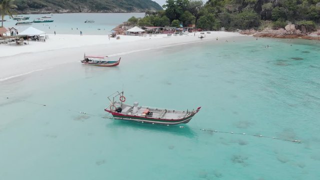 Rotating drone shot around boat at Redang Island, Malaysia, with surrounding turquoise blue waters.