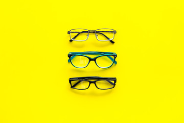 Glasses concept. Set of glasses with different eyeglass frame and transparent lenses on yellow background top view copy space pattern