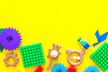 Developing children games mockup. Colorful plastic bricks and blocks on yellow background top view space for text