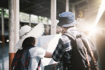 Young couple planning honeymoon vacation trip with map at train station - Travel Concept