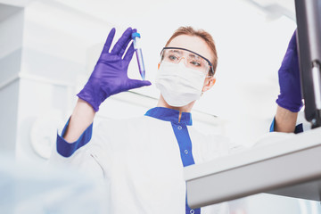 Fototapeta premium Conscious worker. Attentive medical worker standing at her workplace while doing chemical analysis