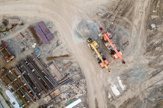 Aerial top view: constraction crane or trucks go together country road  on the construction site to start construction of a new residential complex in the new urban area.