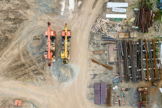 Aerial top view: constraction crane or trucks go together country road  on the construction site to start construction of a new residential complex in the new urban area.  