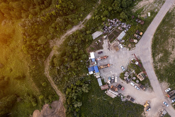 Aerial top view from the height of the parking of special equipment: trucks, construction cranes, cars.  Around the forest and country road