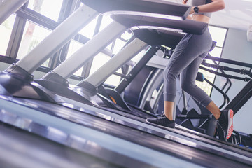 Woman running in machine treadmill  at fitness gym.