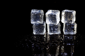 ice cubes reflection on black table background.