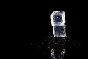 ice cubes reflection on black table background.