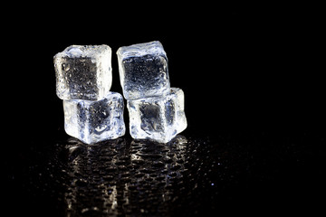 ice cubes reflection on black table background.