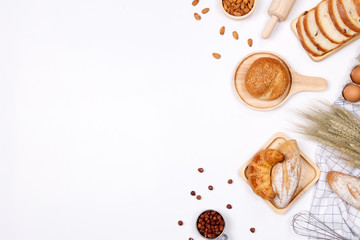 Homemade breads or bun, croissant and bakery ingredients, flour, almond nuts, hazelnuts, eggs on white background, Bakery background frame, Cooking breakfast concept. Flat lay, Top view and copy space