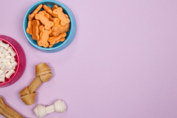 Dog accessories, food and toy on purple background. Flat lay. Top view.
