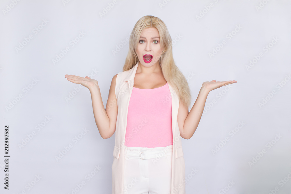 Wall mural business portrait of a blond woman with bright make-up in a pink T-shirt and pink jacket on a white background.