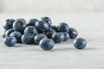 Blueberry on a gray cement background. Ripe and juicy fresh blueberry close-up. A bunch of berries close-up.