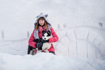 Fototapeta na wymiar Young beautiful girl playing with siberian husky dog in the winter park